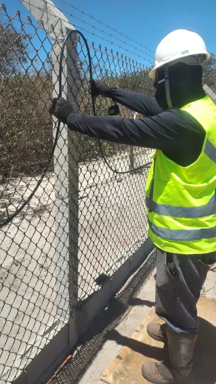 Técnico realizando fusão de fibra óptica em cerca perimetral